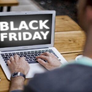 A imagem mostra um homem sentado teclando o computador para saber sobre a Black Firday